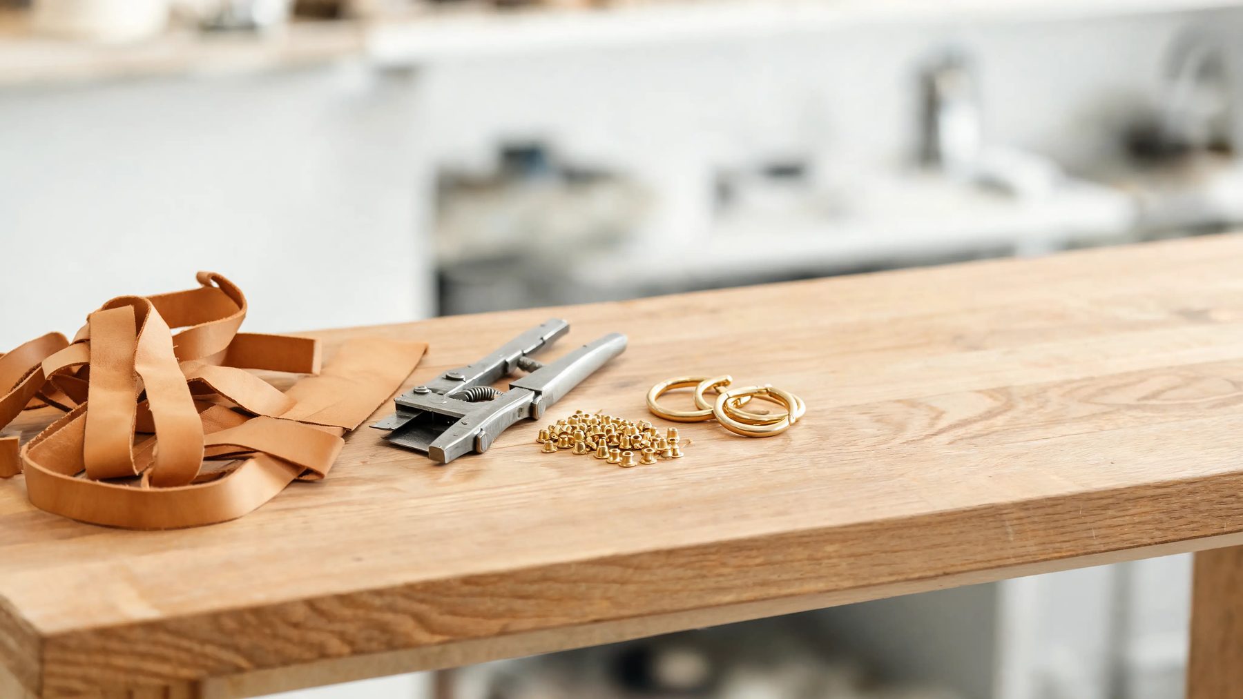Workshop bench with leather strap stock, a strap cutter and brass rivets